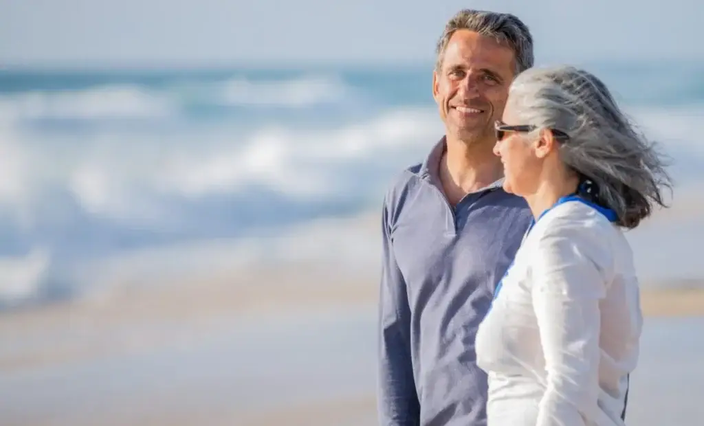 Happy mature couple enjoying time together at the beach, representing improved quality of life through at-home treatment